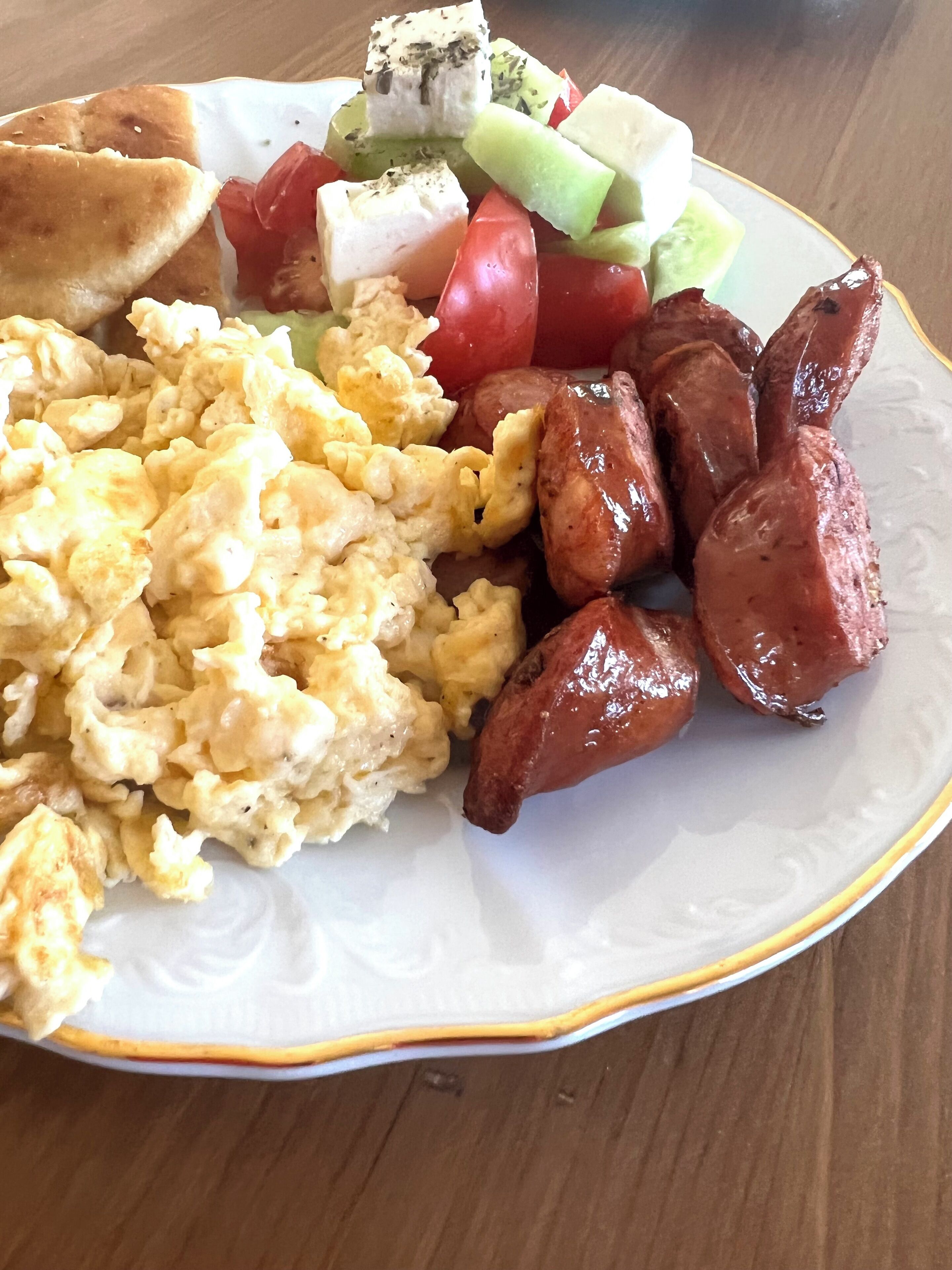 A plate with scrambled eggs, sausages, and a side salad.