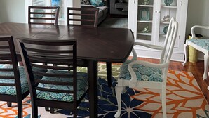 Un coin repas avec une table et des chaises en bois foncé, un tapis à motifs et un buffet blanc aux portes vitrées.
