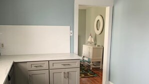Une cuisine avec des meubles de couleur grise, un plan de travail blanc et un tapis bleu foncé.