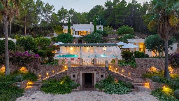 Una villa con piscina, mobiliario exterior y una escalera de piedra que conduce a la entrada.