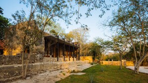 A courtyard with a stone wall, a covered outdoor seating area, and trees. - Viatura Hacienda Xtojil, Yucatan, Merida, with Optional All Inclusive (Timucuy)
