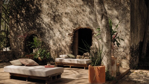 A rustic outdoor seating area with a stone wall, wooden furniture, and potted plants. - Viatura Hacienda Xtojil, Yucatan, Merida, with Optional All Inclusive (Timucuy)