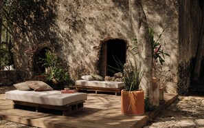 A rustic outdoor seating area with a stone wall, wooden furniture, and potted plants. - Viatura Hacienda Xtojil, Yucatan, Merida, with Optional All Inclusive (Timucuy)