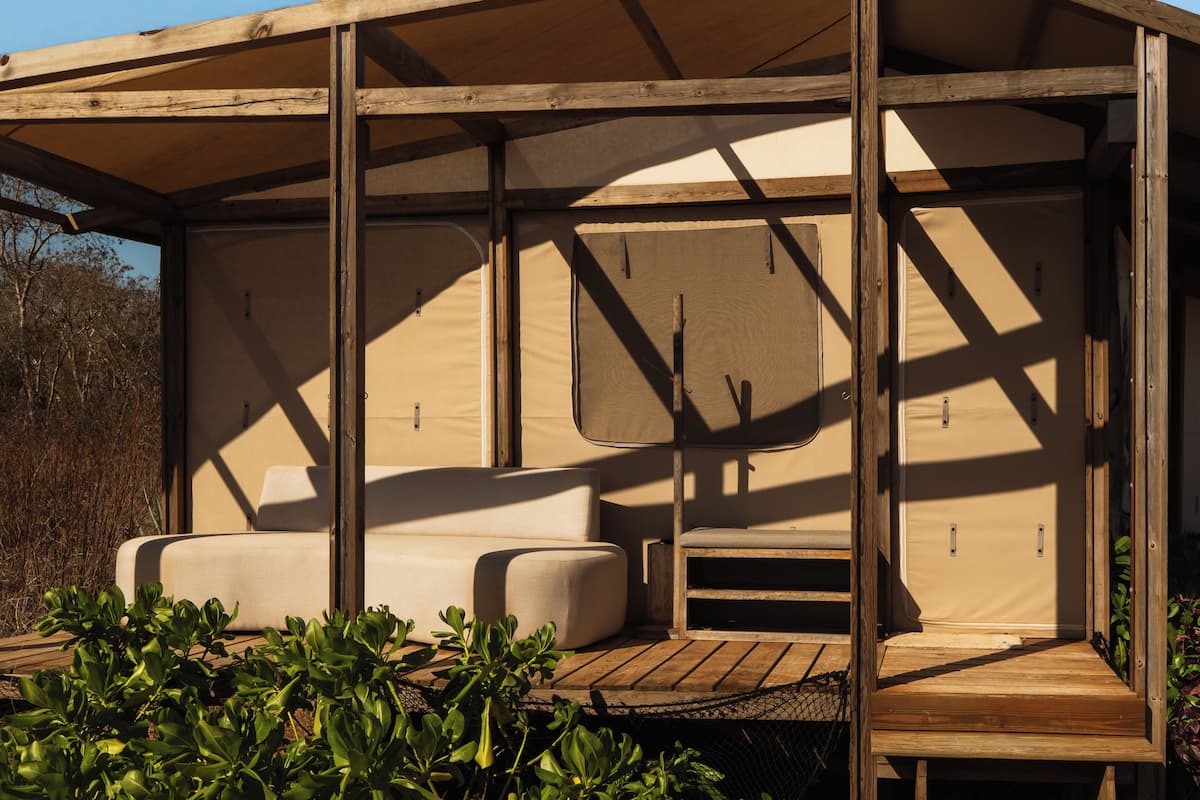 A covered outdoor seating area with cushioned benches and a wooden deck.