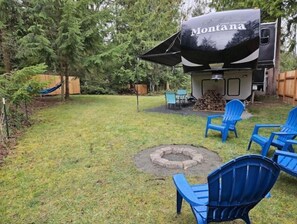 Enjoy al fresco dining and cozy gatherings around the fire pit, surrounded by lush trees and comfortable seating.
