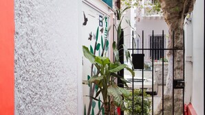 A narrow alleyway with red and white walls, potted plants, and a metal gate. - Hostal Whipala (Quito)