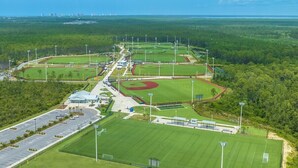 Ein Luftbild eines Sportkomplexes mit mehreren Spielfeldern, Parkplätzen und einem Stadion.