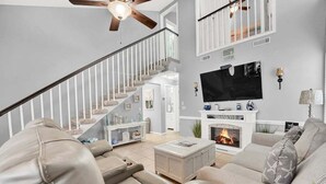 Ein Wohnzimmer mit Kamin, Fernseher und einer Treppe.