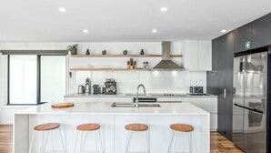 Una cucina moderna con isola centrale, sgabelli da bar, forno integrato e un grande frigorifero.