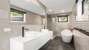 Un bagno moderno con doppio lavabo, una vasca freestanding e una cabina doccia in vetro.