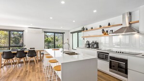 Una cucina moderna con isola centrale, sgabelli da bar, un'ampia finestra e vista sull'esterno.