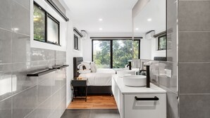 Un bagno moderno con una grande finestra, un letto, un lavabo e uno specchio.