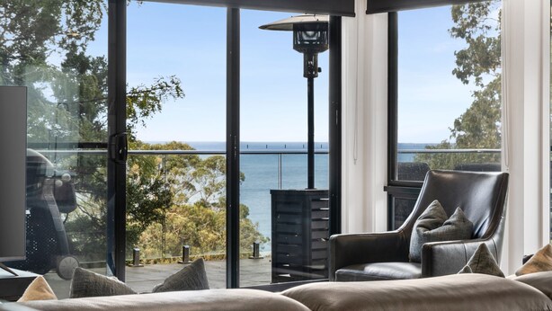 Una camera moderna con un'ampia porta vetrata che si apre su un balcone vista mare.