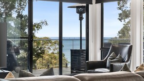 Une chambre moderne dotée d’une grande porte vitrée donnant sur un balcon avec vue sur la mer.