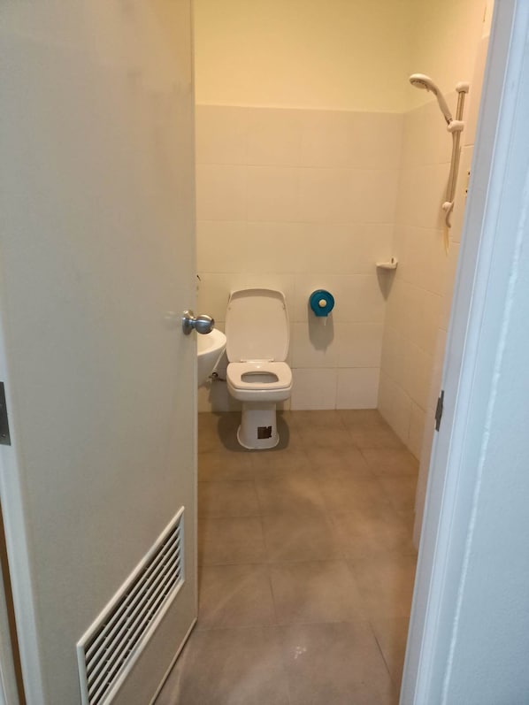 A small bathroom with a toilet, a sink, and a shower. - Kata S.T House 2 (Karon)