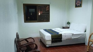 A small, clean room with a bed, a chair, a nightstand, a window, and a wall-mounted picture. - Kata S.T House 2 (Karon)