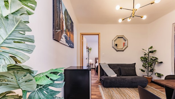 Una sala de estar moderna con una mesa de centro negra, un sofá oscuro y suelo de madera.