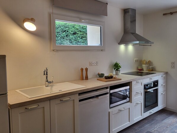 Una cocina moderna con ventana, horno empotrado y campana extractora de acero inoxidable.