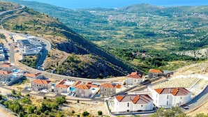 Eine Küstenstadt mit terrassenförmig angelegten Häusern, einer kurvenreichen Straße und Blick aufs Meer.
