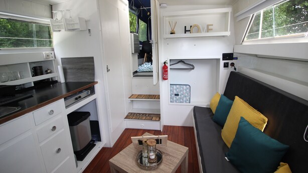 A compact kitchen with a dining area, a small table with a tray, and a sofa with cushions.