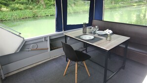 A compact kitchen area with a table, chairs, and a window overlooking a river.