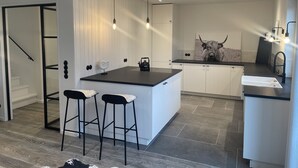 A modern kitchen with a central island, bar stools, pendant lighting, and a bull-themed artwork.
