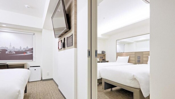 A hotel room with two beds, a flat-screen TV mounted on the wall, a small table, and a bedside table. - Red Planet Sapporo Susukino Central (Sapporo)