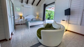 A bedroom with a bed, a sofa, a TV, and a window with a view of greenery. - Villa sea view from 3 to 11 people (Rivière-Salée)