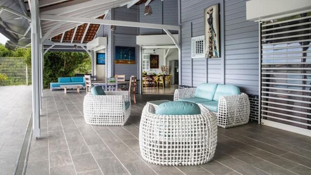 A covered outdoor seating area with wicker furniture and a blue sofa. - Villa sea view from 3 to 11 people (Rivière-Salée)