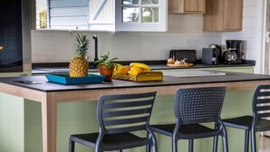 A kitchen island with two black chairs, a pineapple, and a fruit bowl. - Villa sea view from 3 to 11 people (Rivière-Salée)