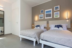 A bedroom with two beds, a wardrobe, and wall-mounted lights.