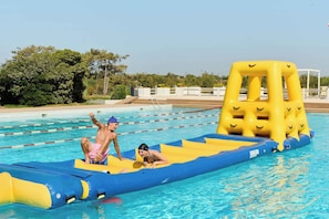 A swimming pool with lane dividers, a yellow and blue inflatable play structure, and a clear sky.