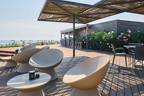 A deck with modern furniture, a bar area, and a view of the sea.