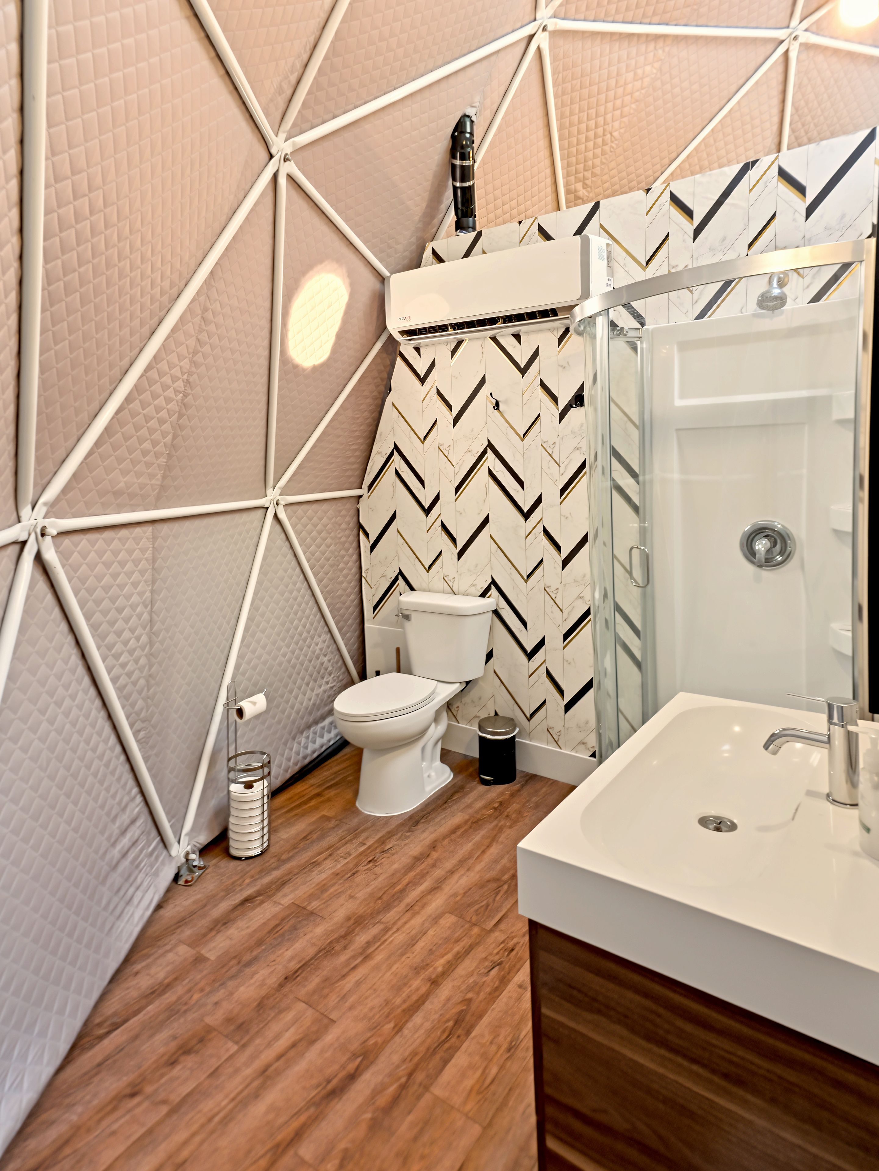 Un bagno moderno con un design geometrico al muro, un water, un lavandino e uno spazio doccia.