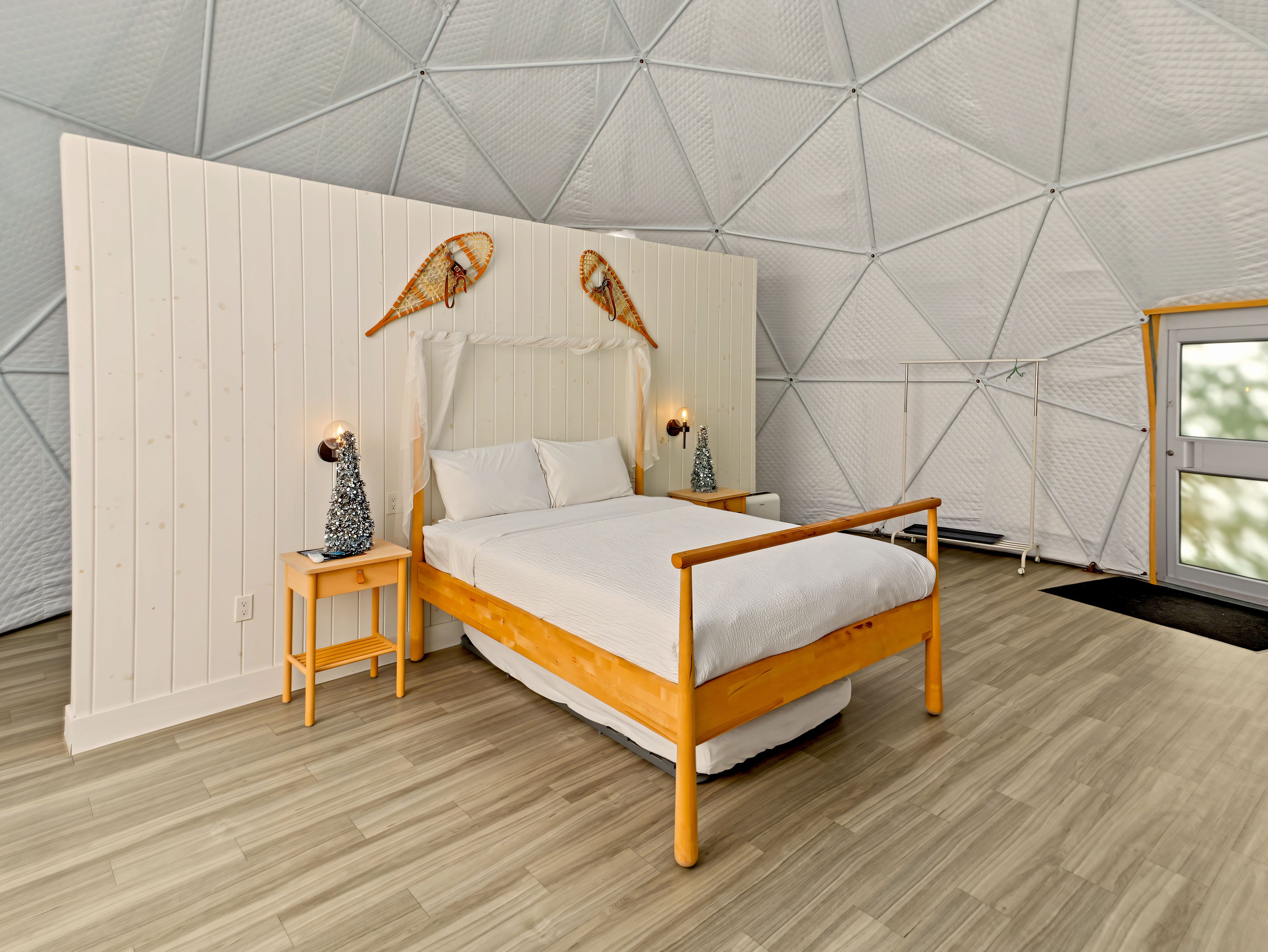A bedroom with a wooden bed, white walls, and a geometric ceiling design.