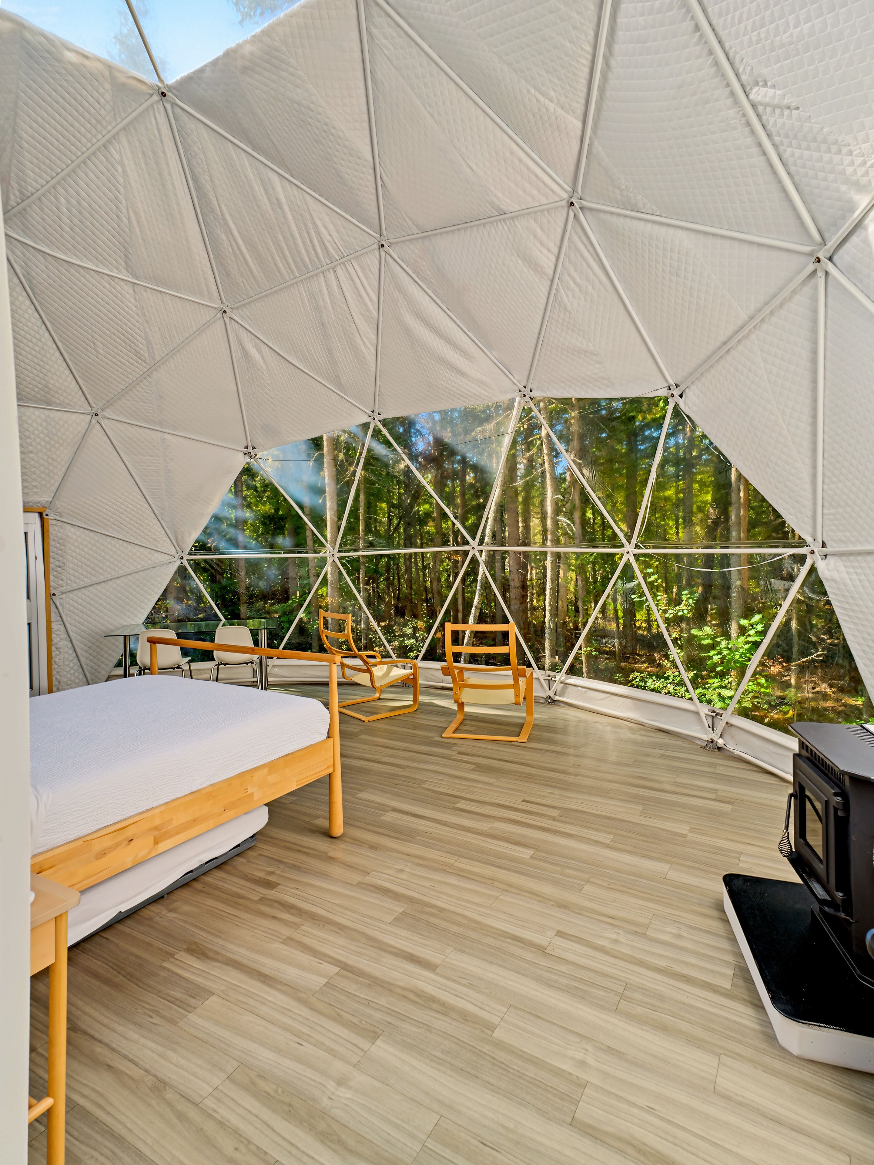 Eine Zeltunterkunft mit Bett, Sitzgelegenheit und Fernseher.