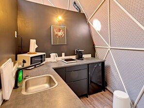 A compact kitchenette with a microwave, kettle, coffee maker, and a sink. - Glamp Camp (Waterborough)