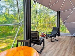 A room with a large window, a wooden floor, and a black chair. - Glamp Camp (Waterborough)