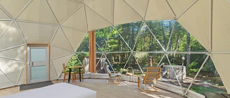 A tented accommodation with a bed, seating area, and a fireplace.