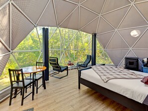 A tented accommodation with a bed, chairs, a table, and a fireplace. - Glamp Camp (Waterborough)