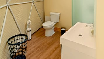 A compact bathroom with a white toilet, a white sink, and a black trash bin.
