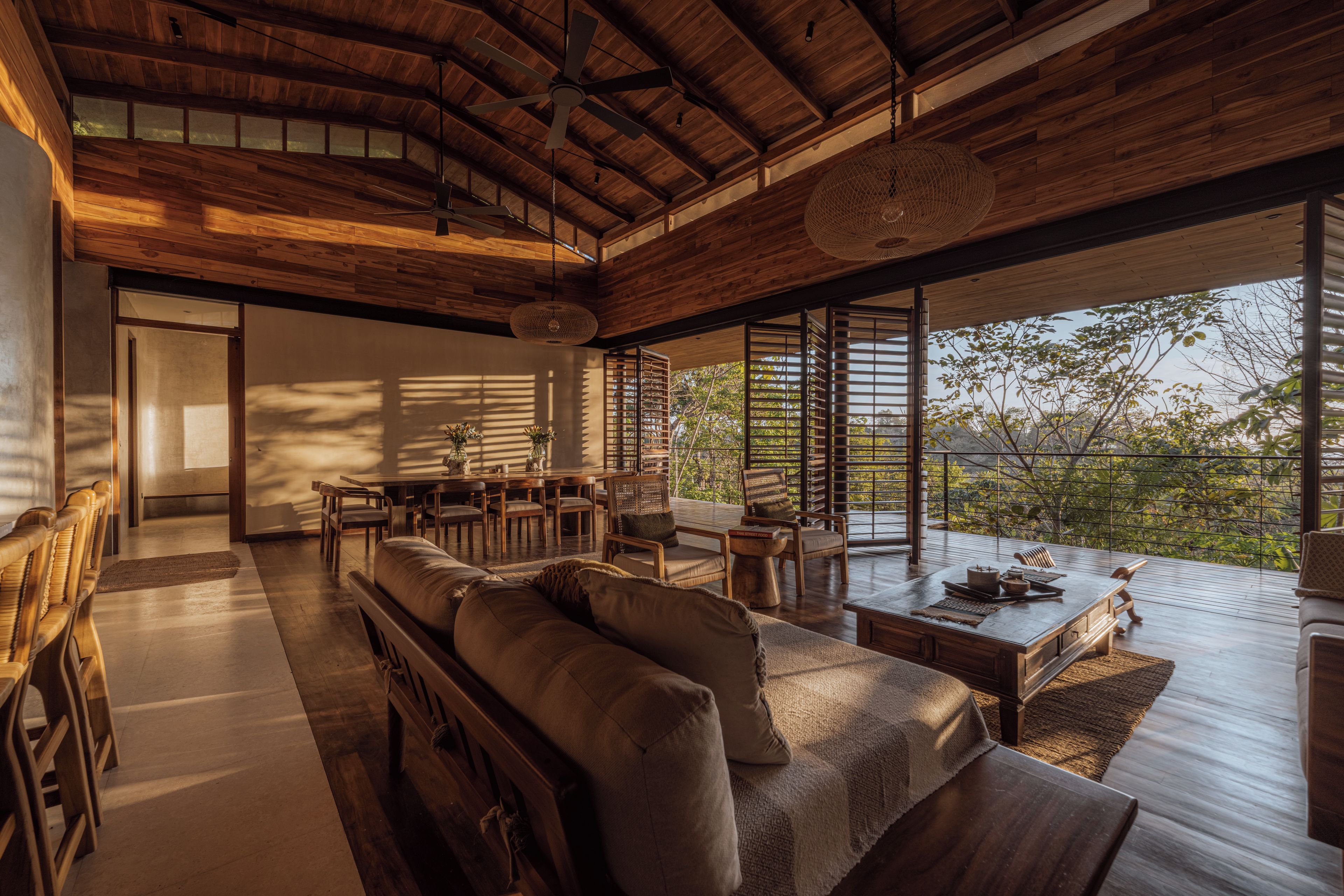 A spacious living area with a high ceiling, wooden beams, a dining table, and a seating arrangement.