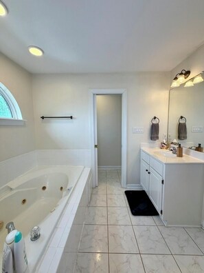 Une salle de bain avec une baignoire, un meuble-lavabo, un miroir et une fenêtre.