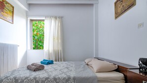 A bedroom with a bed, a window with curtains, a radiator, and a dresser. - 4u Apartment Athens! 2 Minutes From Metro Station (Nea Ionia)