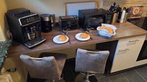 A kitchenette with a coffee maker, toaster, microwave, and a small dining area with two chairs and a table. - Bright and modern apartment on the ground floor in the center (Kassel)