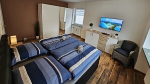 A bedroom with a bed, a TV, a chair, and a desk. - Bright and modern apartment on the ground floor in the center (Kassel)