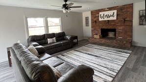 Un salon moderne avec un canapé en cuir, une cheminée et un ventilateur de plafond.