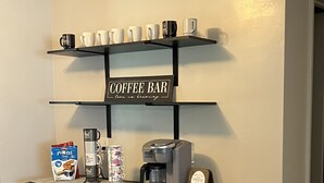 Un espace café aménagé avec une machine à café, des tasses et un panneau indiquant « CAFÉ ».