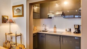 A modern kitchen with stainless steel appliances, a wooden dining table, and a small side table with a lamp.