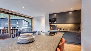 A modern kitchen with dark cabinets, a central island, and a view of a building outside.